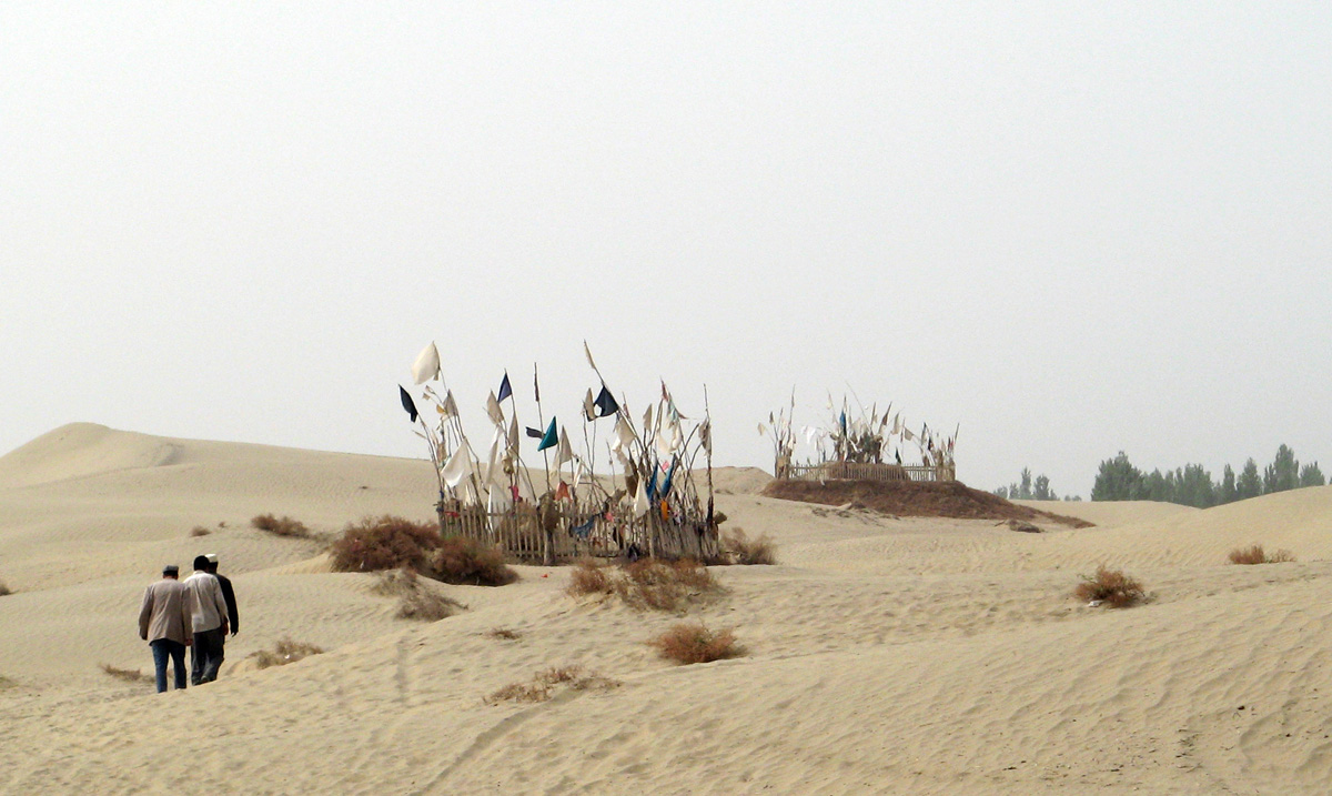 Niya - Hotan - Karghilik - Yarkan - Yengisar, Returning from Imam Asim Shrine Graves of revered figures, decorated with banners.
